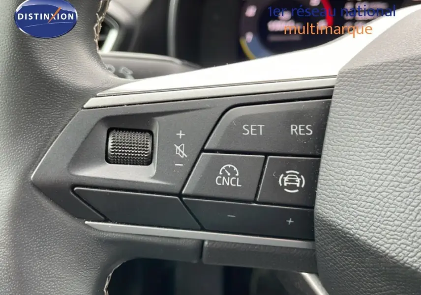 Gros plan sur les commandes de régulateur de vitesse au volant d’une SEAT LEON ST bleu Fjord, intérieur gris-noir.