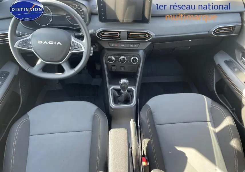 Vue intérieure de la Dacia Sandero 2025 avec tableau de bord, volant multifonction et sièges gris schiste.