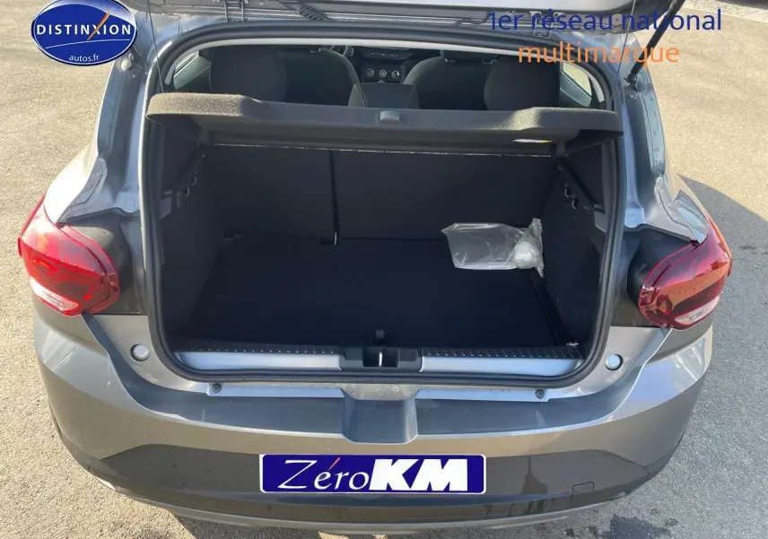 Coffre ouvert d'une Dacia Sandero gris schiste vue de l'arrière, montrant l'espace de chargement vide.