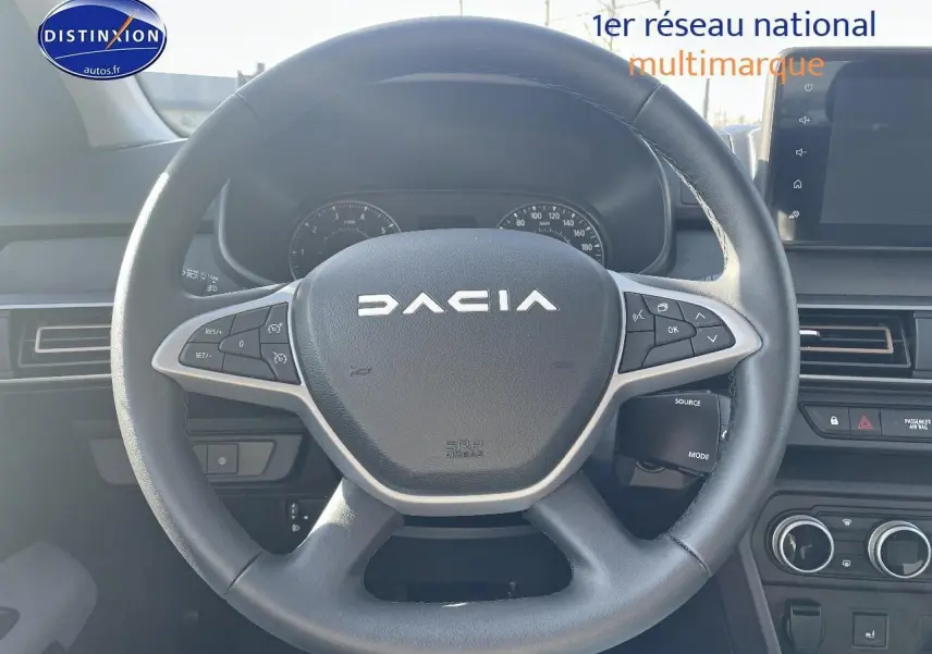 Volant noir avec logo DACIA en vue frontale, tableau de bord et écran tactile visibles dans l'habitacle d'une Sandero 2025