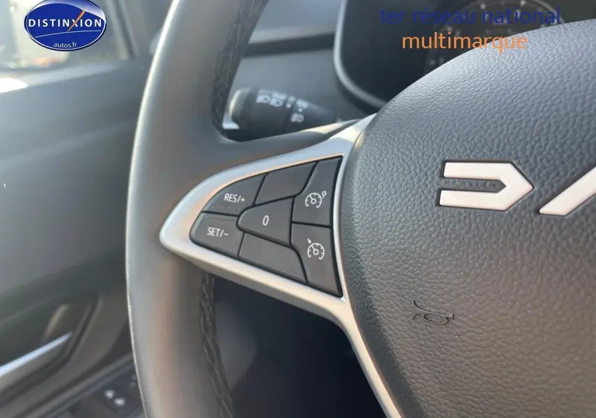 Gros plan sur le volant en cuir noir de la Dacia Sandero 2025 avec commandes de régulateur de vitesse intégrées.