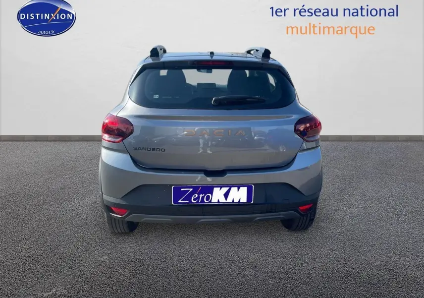 Vue arrière d'une Dacia Sandero gris schiste 2025 avec barres de toit et feux arrière rouges.
