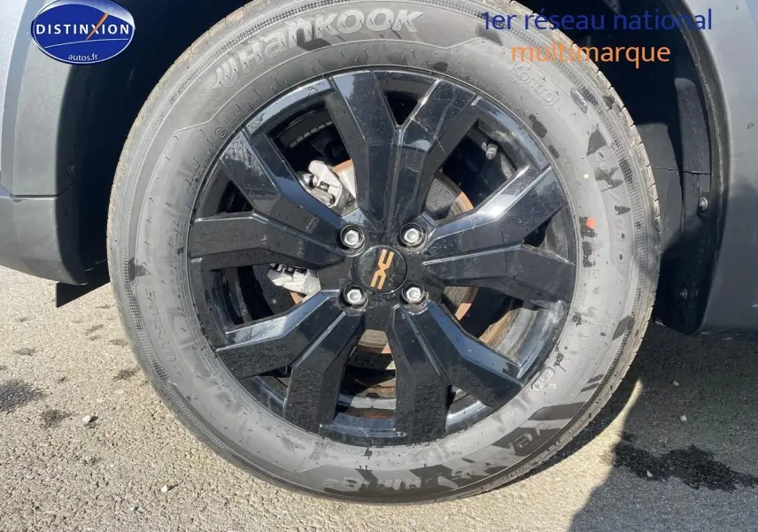 Gros plan sur la jante alu noire de la roue avant droite du Dacia Sandero Stepway gris schiste 2025.