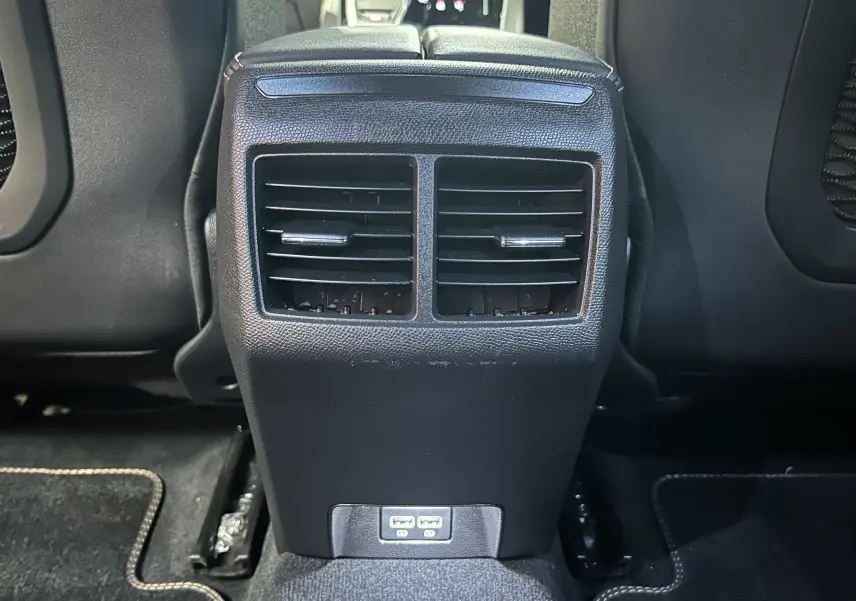 Vue rapprochée des aérateurs arrière et des ports USB de la console centrale d'une Peugeot 508 SW gris Selenium 2024.