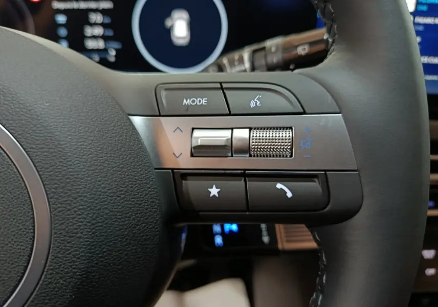 Gros plan sur les commandes du volant cuir noir du Hyundai Tucson 2025, avec écran digital en arrière-plan.