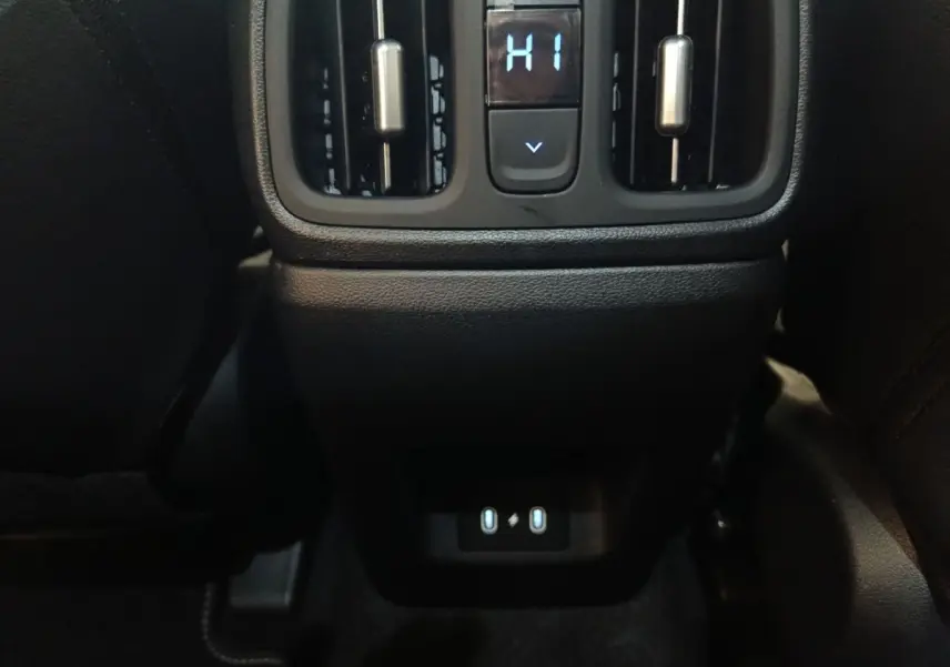 Vue rapprochée de la console arrière noire du Hyundai Tucson 2025 gris clair, avec commandes de ventilation et ports USB.