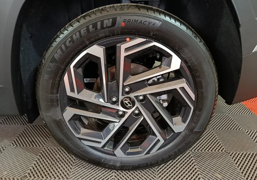 Gros plan sur la roue avant droite du Hyundai Tucson gris clair 2025, jante alliage au design géométrique moderne.