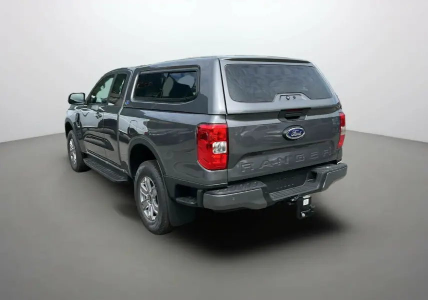 Ford Ranger gris carbone vu en 3/4 arrière droit avec hard-top vitré et attelage visible.