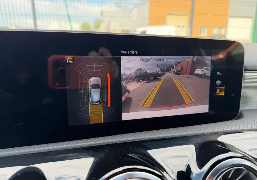 Affichage de la caméra de recul et capteurs de stationnement sur l'écran intérieur de la Mercedes Classe A 220D AMG Line blanche.