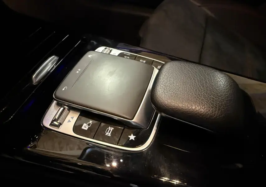 Gros plan sur la console centrale noire de la Mercedes Classe A 220D AMG Line 2019, montrant le pavé tactile et le repose-poignet en cuir.