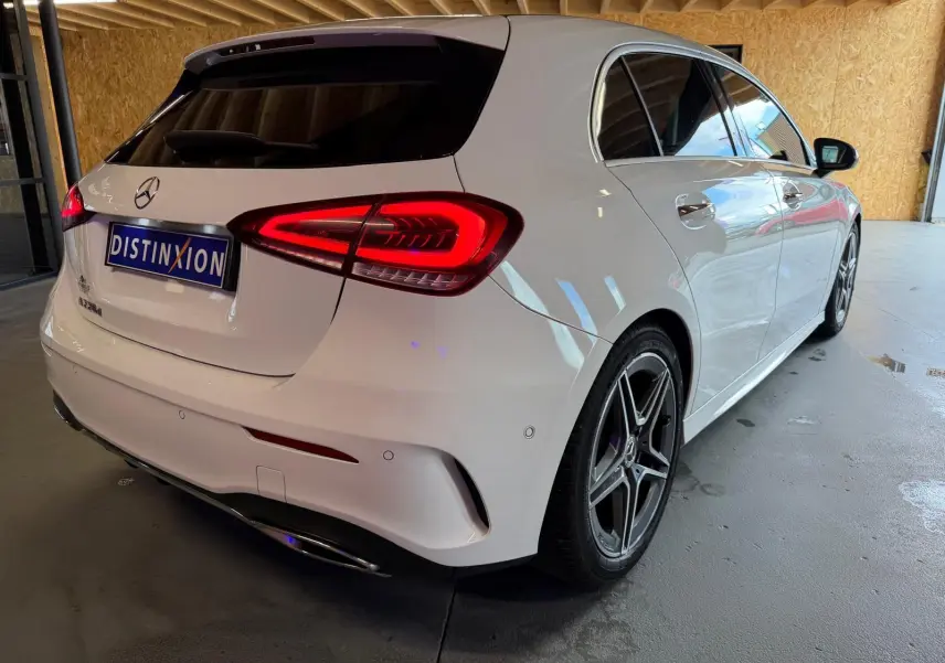 Mercedes Classe A 220D AMG Line blanc vue 3/4 arrière droit, feux arrière allumés et jantes sport visibles.
