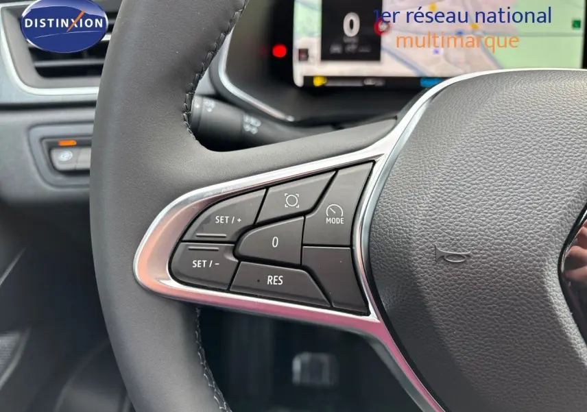 Gros plan sur les commandes au volant à gauche du Renault Captur II gris rafale métal avec toit noir, tableau de bord numérique en arrière-plan.