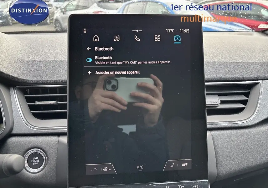 Vue de face de l'écran tactile central du Renault Captur gris Rafale métal, avec tableau de bord et bouton start visible.