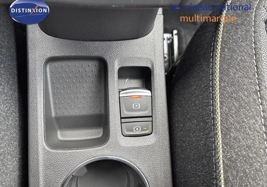 Gros plan sur la console centrale noire du Renault Captur II hybride, montrant les boutons de frein à main et auto hold.