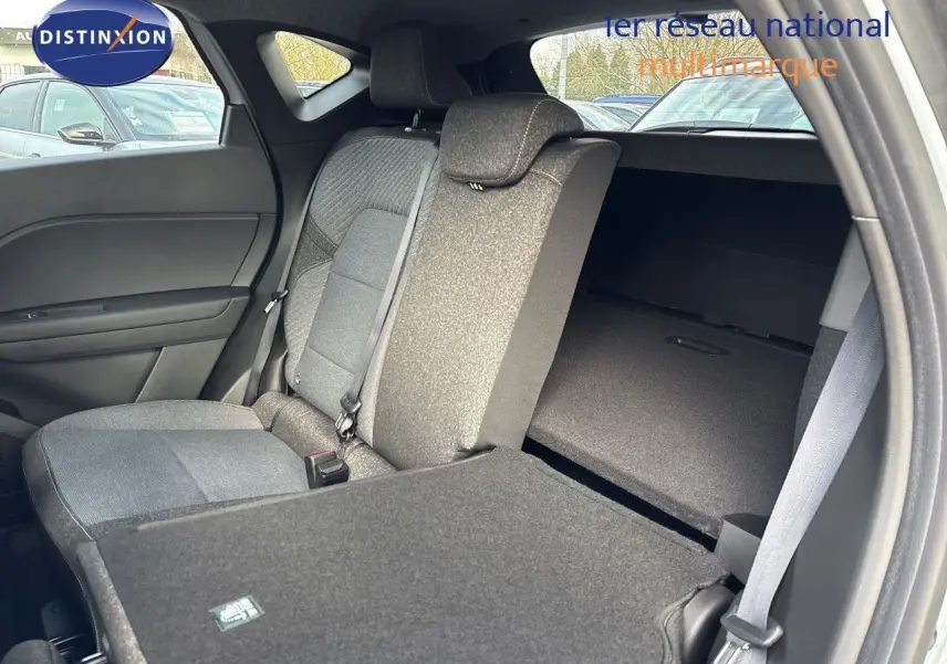 Vue intérieure côté gauche du Renault Captur II hybride 2025, montrant la banquette arrière avec une partie rabattue en tissu gris.