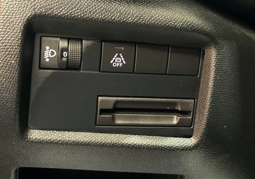 Gros plan sur les commandes intérieures noires du Citroën C5 Aircross 2024, avec réglage phare et assistance de maintien de voie désactivée.