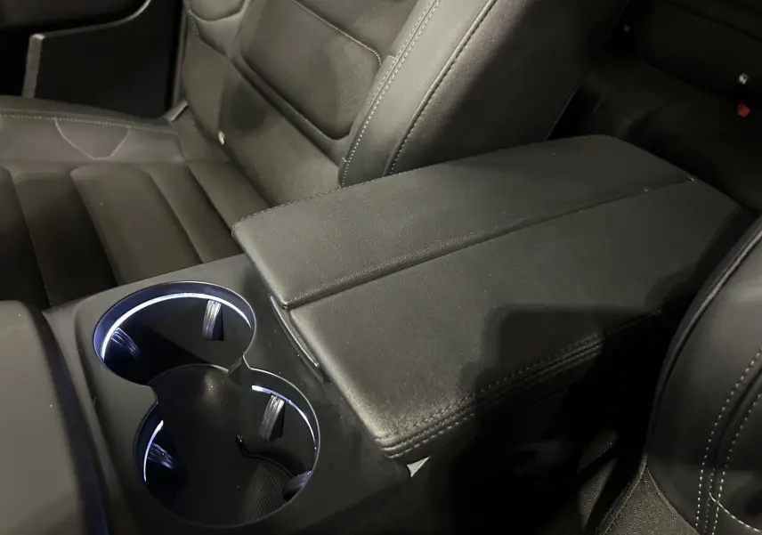 Gros plan sur l'accoudoir central noir et les porte-gobelets éclairés à LED de l'intérieur du Citroën C5 Aircross 2024.