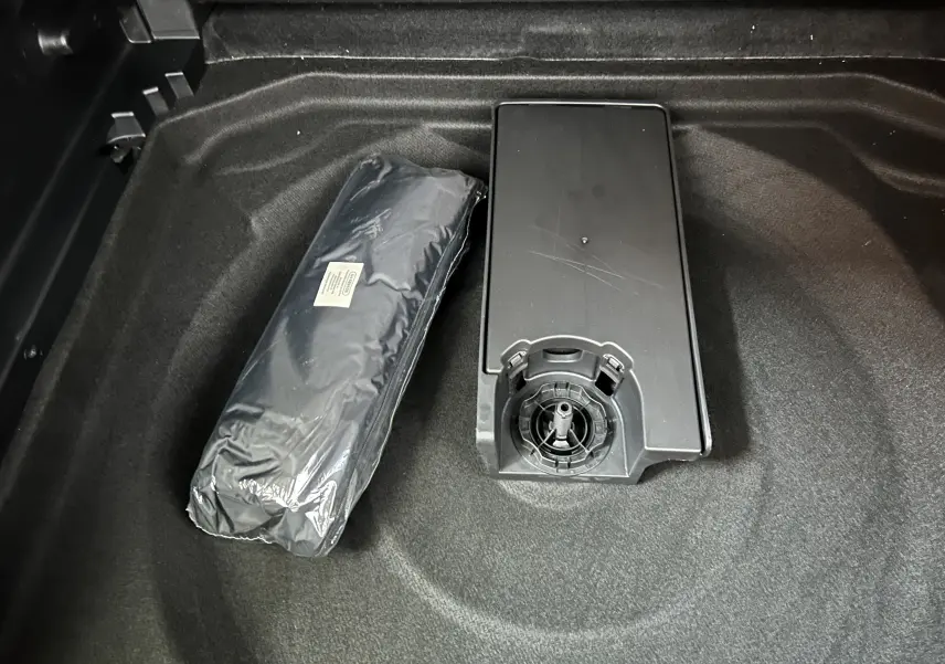 Vue rapprochée du coffre noir d'une Citroën C5 Aircross 2024 avec un kit de secours et un boîtier plastique.