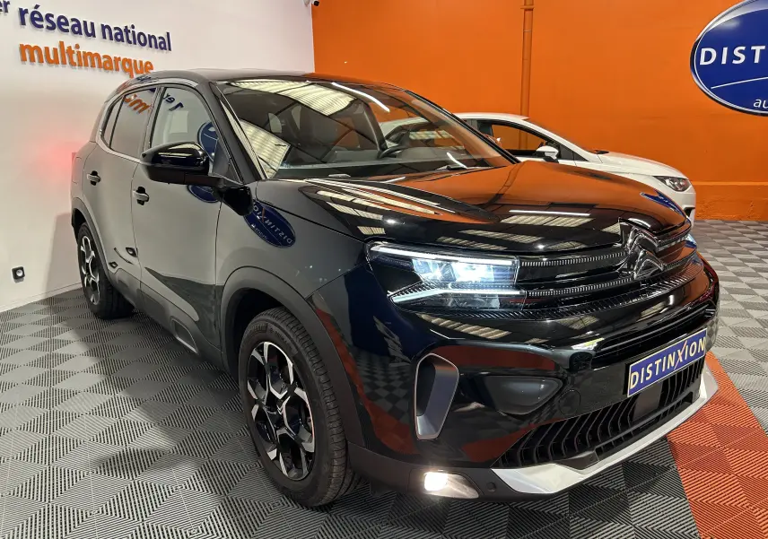 Citroën C5 Aircross Ph.2 Max Hybride noir Perla Nera, vue 3/4 avant droit avec phares LED allumés en showroom.