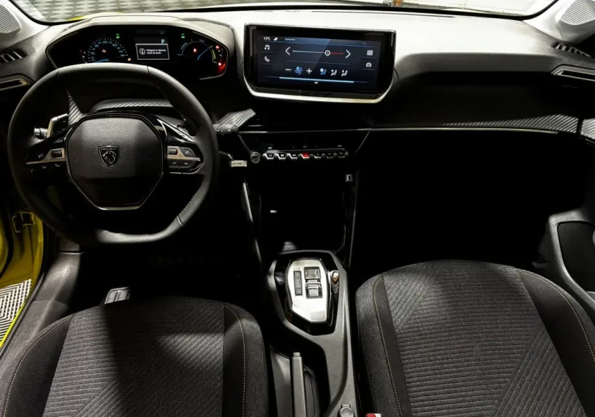 Vue intérieure avant de la Peugeot 208 Hybrid jaune, montrant le volant cuir multifonctions et l'écran tactile central.