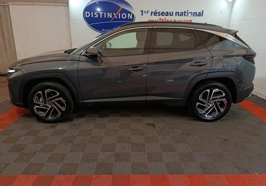 Vue de profil côté gauche d'un Hyundai Tucson gris foncé 2025 avec jantes alliage au design moderne.