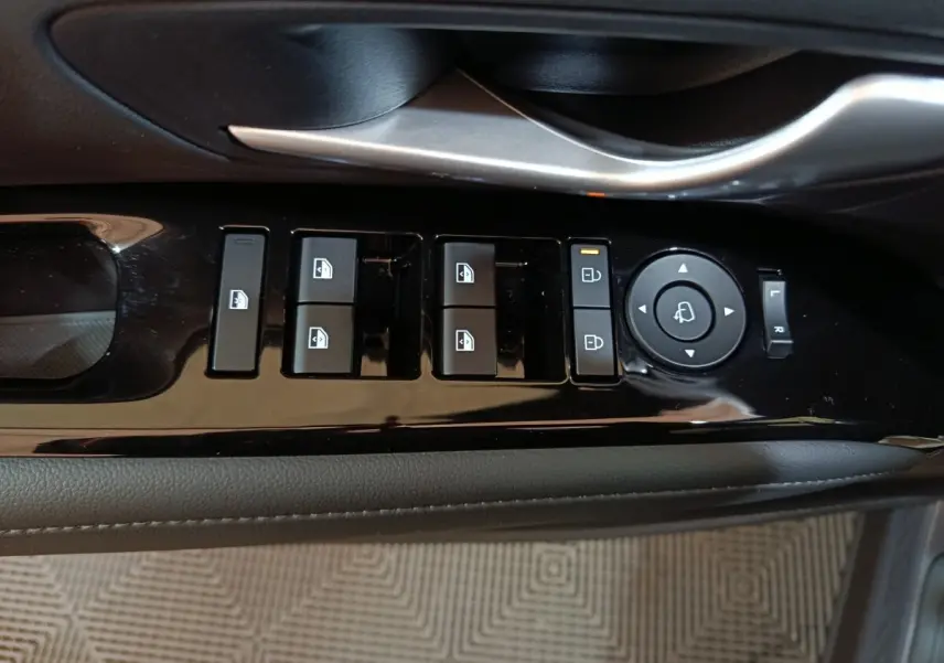 Gros plan sur les commandes de lève-vitres et réglage des rétroviseurs côté conducteur du Hyundai Tucson gris foncé 2025.