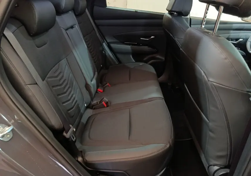 Vue intérieure côté gauche des sièges arrière en tissu noir du Hyundai Tucson 1.6 Hybrid 2025 avec appuie-têtes réglables.