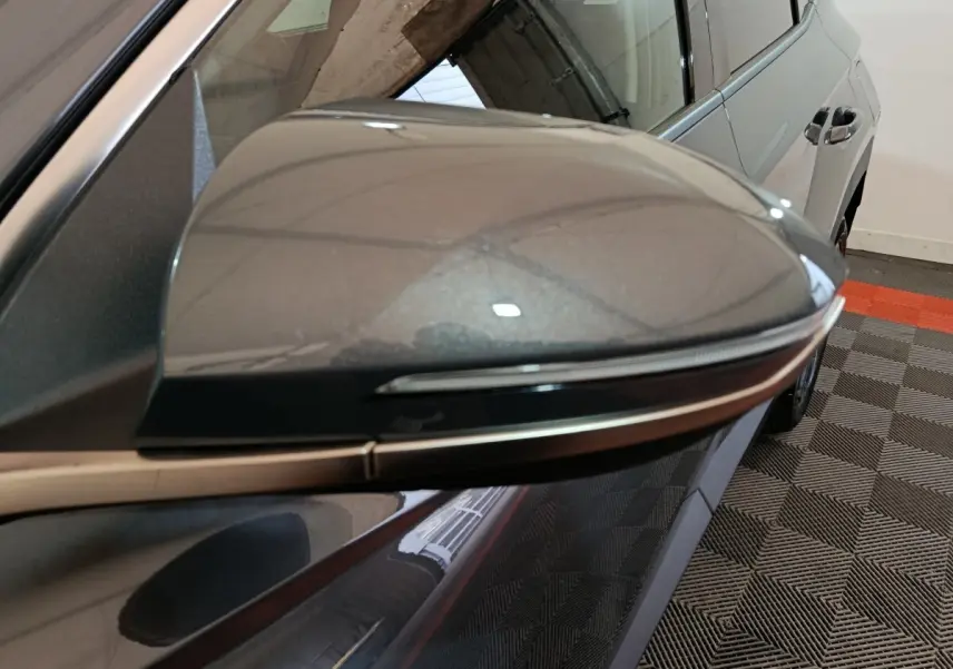 Rétroviseur droit gris foncé du Hyundai Tucson 2025, vue rapprochée avec partie latérale et porte arrière visible.