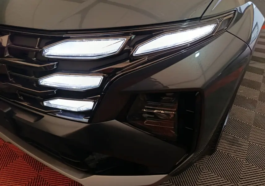 Gros plan sur l'avant droit gris foncé du Hyundai Tucson 2025 avec phares LED et calandre distinctive.