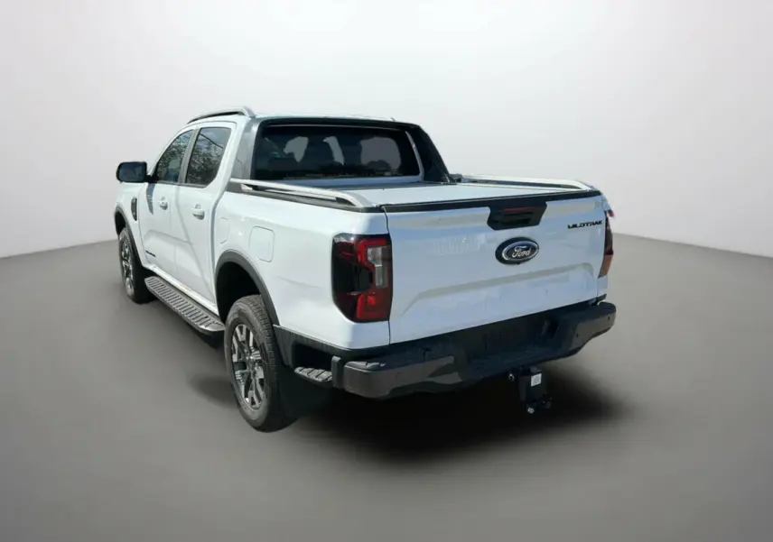 Ford Ranger blanc en 3/4 arrière droit avec benne, attelage et jantes alu 18 pouces visibles.