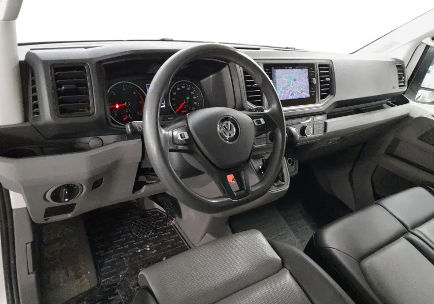 Vue intérieure du poste de conduite du Volkswagen Crafter blanc, avec volant multifonction et écran tactile central.