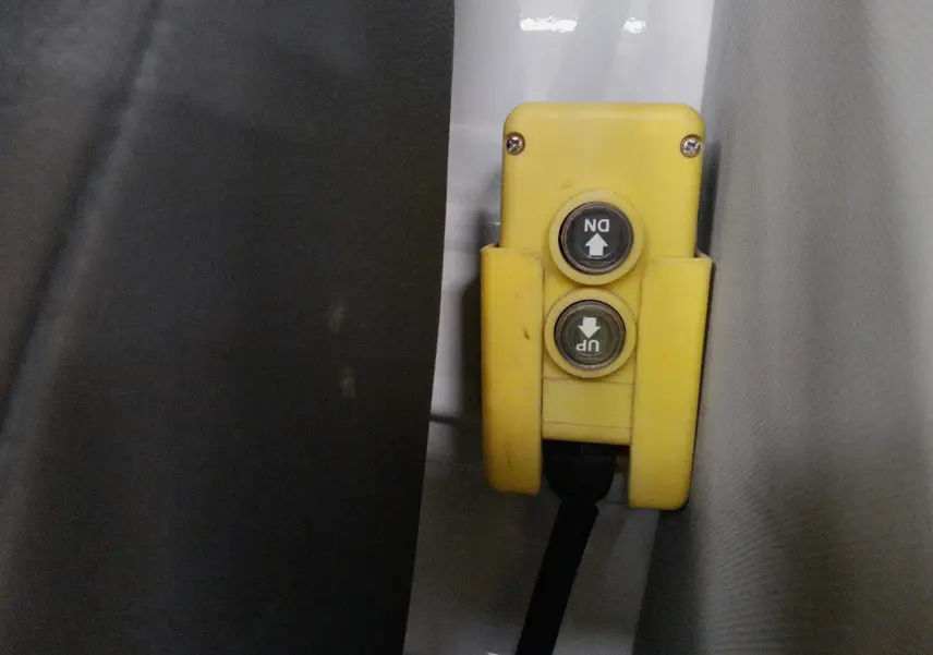 Gros plan sur la commande jaune de levage avec boutons up et down à l'intérieur d'un Volkswagen Crafter blanc.