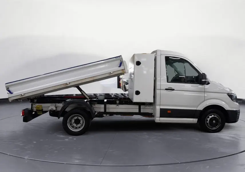 Vue latérale droite d’un Volkswagen Crafter blanc 2021 avec benne relevée et coffre arrière, roues jumelées visibles.