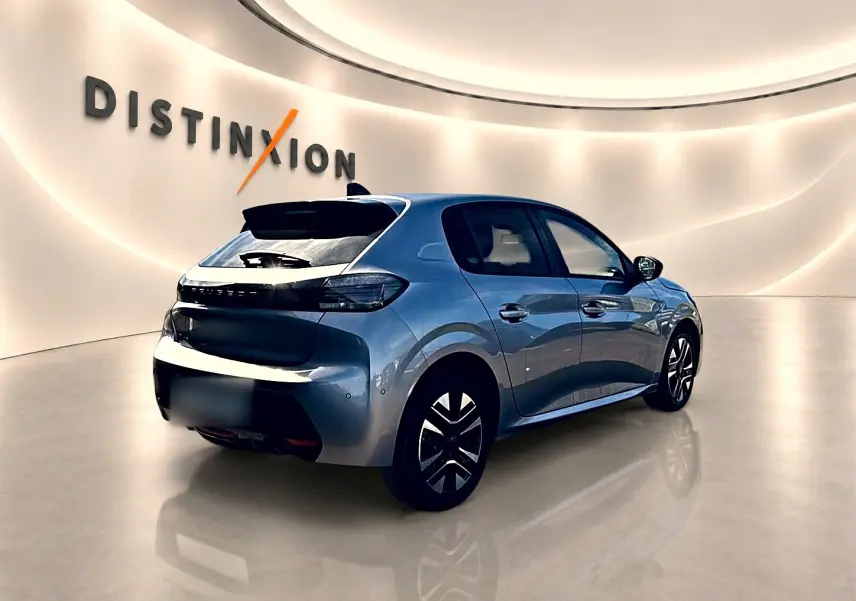 Vue 3/4 arrière droite d'une Peugeot 208 1.2 100 Allure gris artense dans un showroom lumineux.