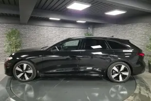 Audi A5 Avant noire vue de profil côté gauche dans un showroom avec jantes 5 branches doubles brillantes.