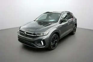 Volkswagen T-Roc gris indium en 3/4 avant droit avec jantes noires et barres de toit noires visibles.