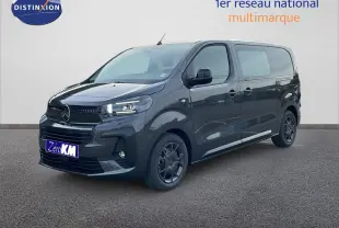 Fourgon gris titane en 3/4 avant droit, avec calandre et jantes noires, sur fond neutre intérieur showroom.