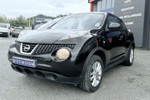 Nissan Juke noir en 3/4 avant droit, avec phares ronds allumés et jantes argentées visibles.