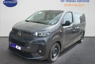 Fourgon gris titane en 3/4 avant droit avec calandre et jantes noires, stationné devant un mur blanc.
