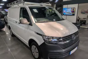 Volkswagen Transporter 6.1 blanc Candy en 3/4 avant droit avec galerie de toit en intérieur showroom.