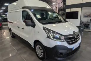 Vue 3/4 avant d'un Renault Trafic Fourgon blanc Glacier L2H2, avec calandre noire et phares LED dans un showroom.