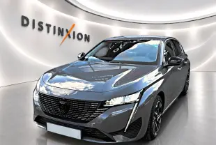 Vue 3/4 avant d'une Peugeot 308 gris selenium avec calandre noire et feux LED verticaux, en showroom lumineux.