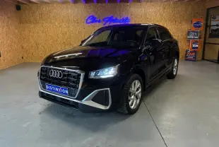 Audi Q2 noir en 3/4 avant droit dans un showroom avec éclairage LED et plaque Distinxion visible.