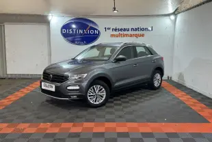 Volkswagen T-Roc gris foncé vue 3/4 avant droit dans un showroom avec sol noir et orange.