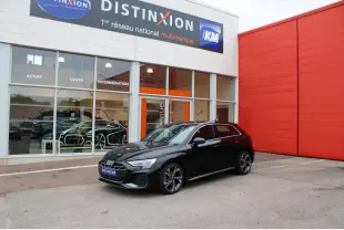 Audi A3 Sportback noir mito metal vue 3/4 avant avec jantes 5 branches et calandre S line devant un bâtiment rouge.