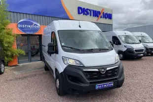 Vue 3/4 avant d'un Opel Movano Fourgon blanc stationné devant un garage avec logo Distinxion visible.