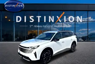 Peugeot 5008 blanc en 3/4 avant droit, avec jantes alu noires et toit noir, devant une vitrine Distinxion.