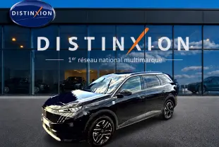Peugeot 5008 Hybrid 145 GT noir en 3/4 avant droit, avec jantes alu et vitres surteintées devant un showroom Distinxion.