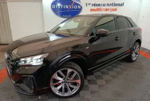 Audi Q2 35 TFSI S Line Plus noir en 3/4 avant droit, avec jantes alliage et feux LED allumés dans un showroom.