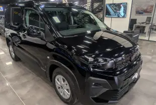 Vue de face d’un Peugeot Rifter noir 2025 dans un showroom, mettant en valeur sa calandre et ses phares modernes.